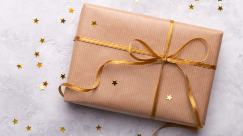 gift wrapped in gold paper with a gold ribbon and gold confetti stars scattered