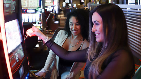 two girls playing at a slot machine