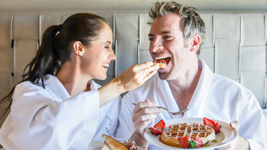Couple feeding each other breakfast in bed