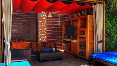A party cabana with a couch, lounge chairs, and privacy curtains at DayDream pool club at The M Resort in Henderson, Nevada, near Las Vegas.