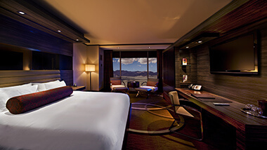 The king-size bed, executive desk with leather chair and conversation area in front of the window showing a view of the mountains of Las Vegas in the Executive Resort Room at The M Resort Spa Casino Hotel.